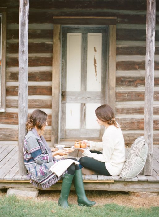 Chicas sentadas en un porche conversando mientras comen y toman té 