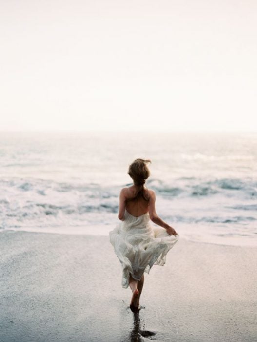 Chica corriendo por la playa hacia el mar 