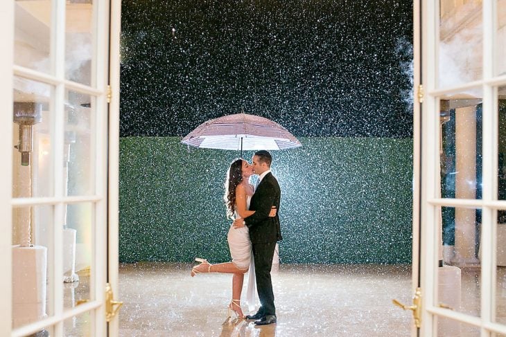 pareja andose un beso con paraguas bajo la lluvia 