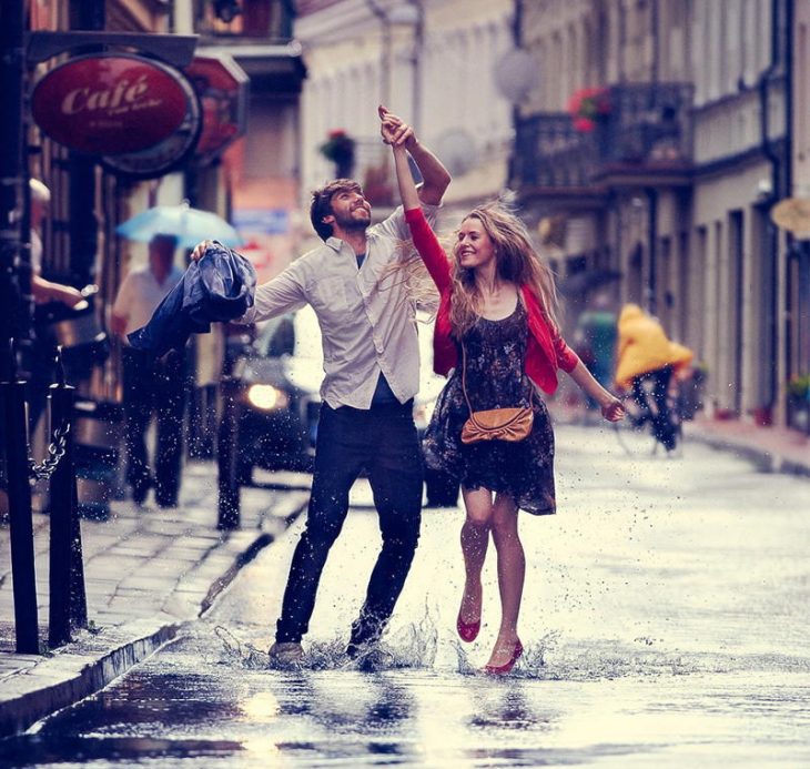 pareja en la lluvia bailando y sonriendo 