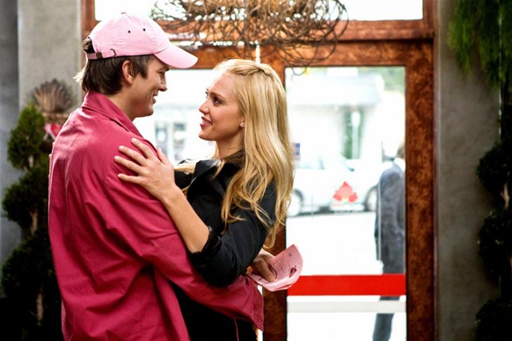 hombre con gorra rosa y mujer rubia abrazados 