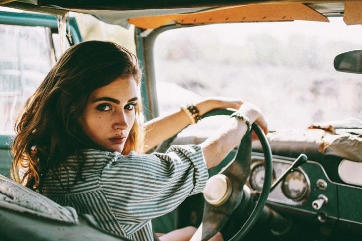 chica al volante de coche antiguo