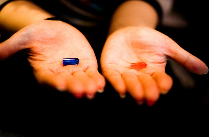 manos con píldora azul y roja