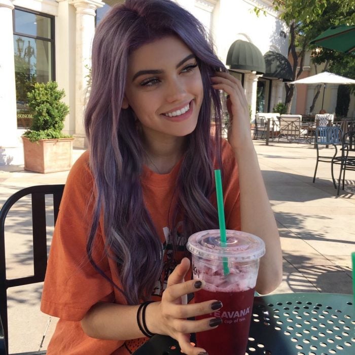 Chica sentada tomando un café de starbucks y sonriendo 