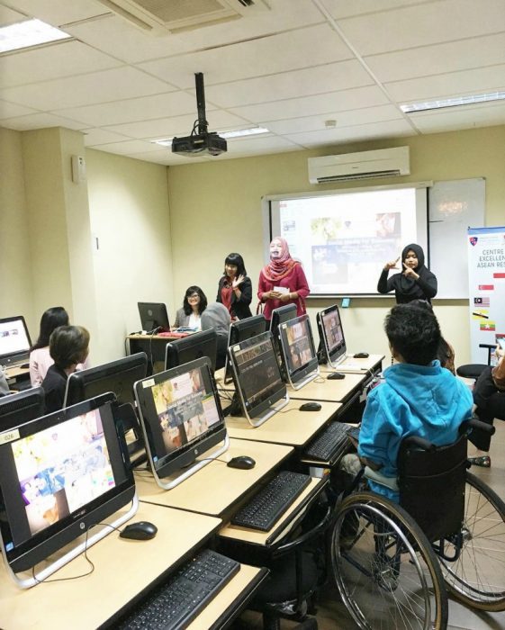 sala de juntas con computadoras y hombre en silla de ruedas 