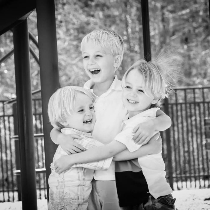 tres niños abrazados sonriendo