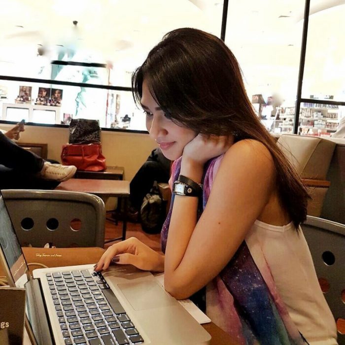 mujer morena seria trabajando en computadora 