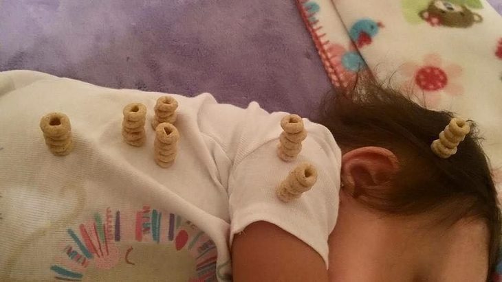 bebe durmiendo con pilas de cereal en sus hombros 