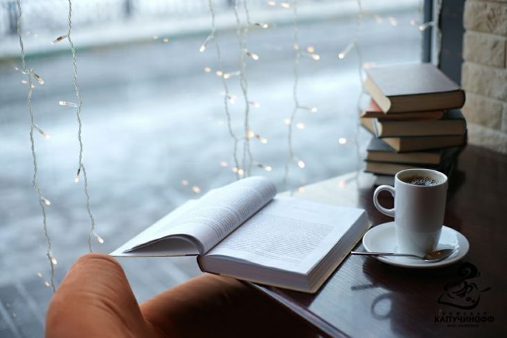 libro y café sobre mesa frente a ventana