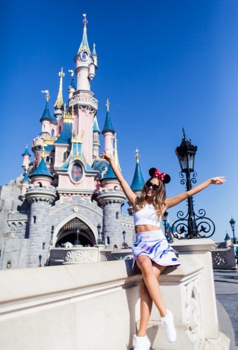 Chica sentada frente al castillo de Disney 