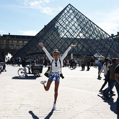 Chica saltando frente al museo de Luvre en Paris 