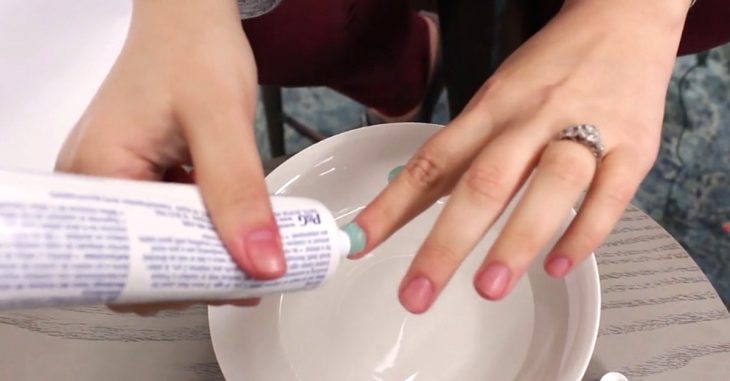 Chica removiendo esmalte con pasta de dientes 