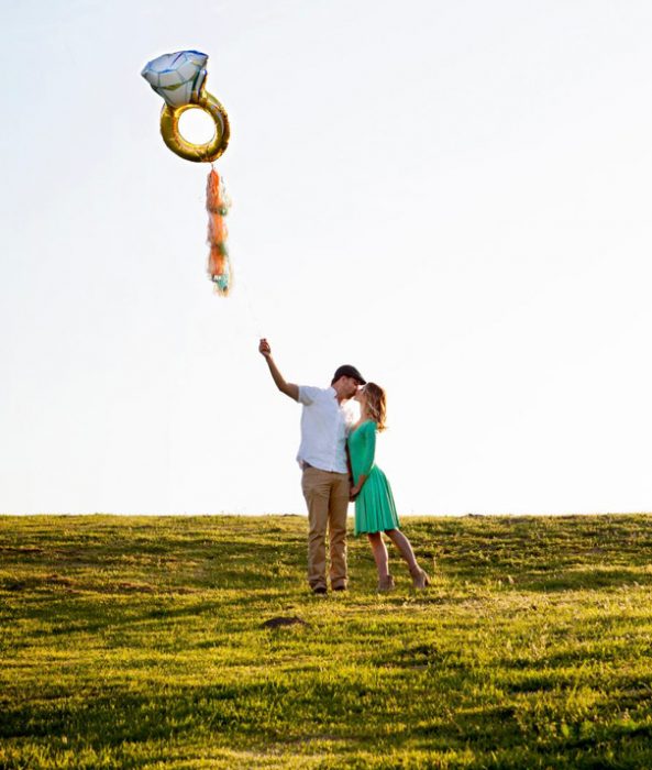 Pareja anunciando su compromiso con un globo de helio 