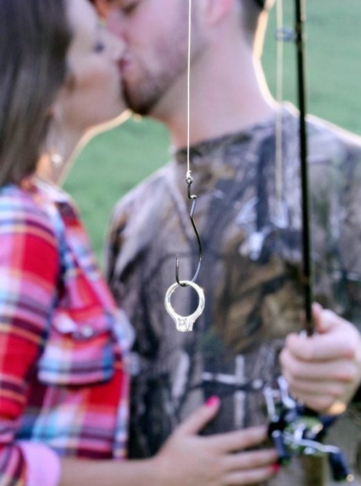 Pareja de novios anunciando su compromiso mientras el sostiene un anillo con una red de pesca 
