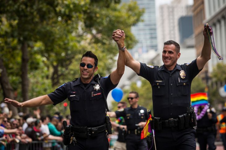 policías hombres tomados de la mano participan desfile gay