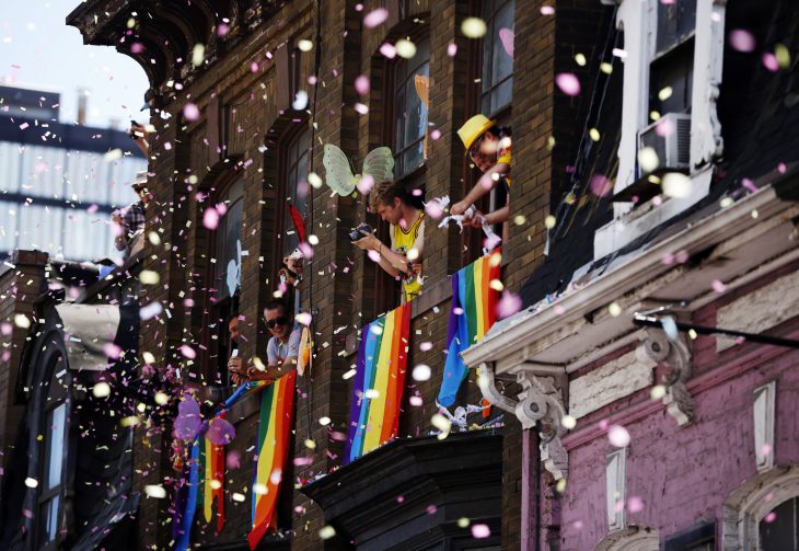 personas avientan confeti desde su ventana durante desfile gay