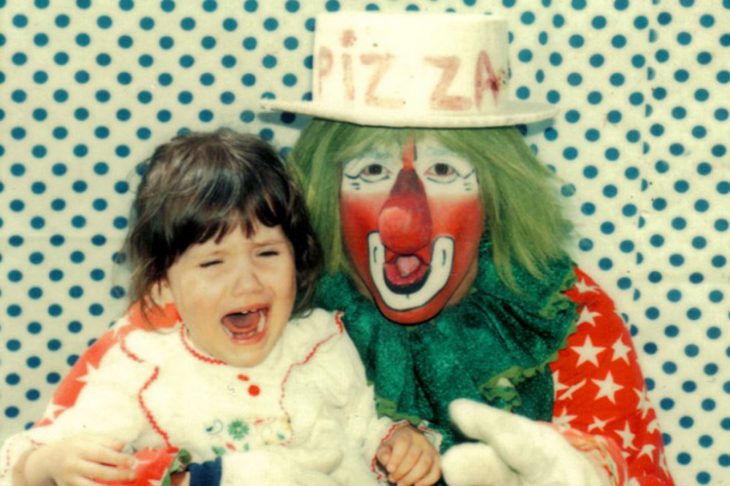 niña llorando y un payaso con peluca verde 