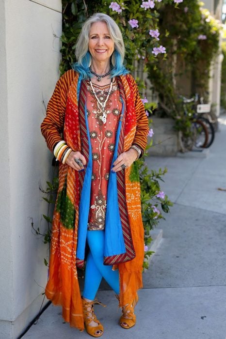 Mujer de la tercera edad usando un vestido de colores con un saco de colores y el cabello azul 