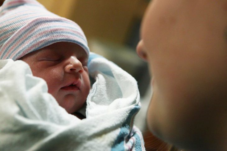 mujer con bebe entre sabanas y gorro 