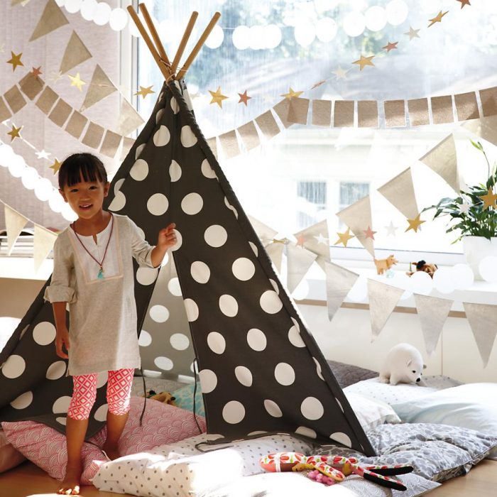 Niña con una tienda de campaña en su casa. 