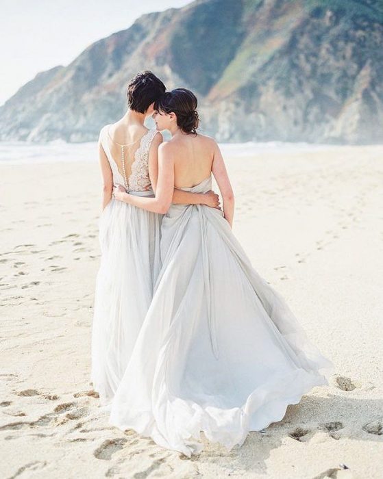 Chicas recién casadas caminando a la orilla de la playa 