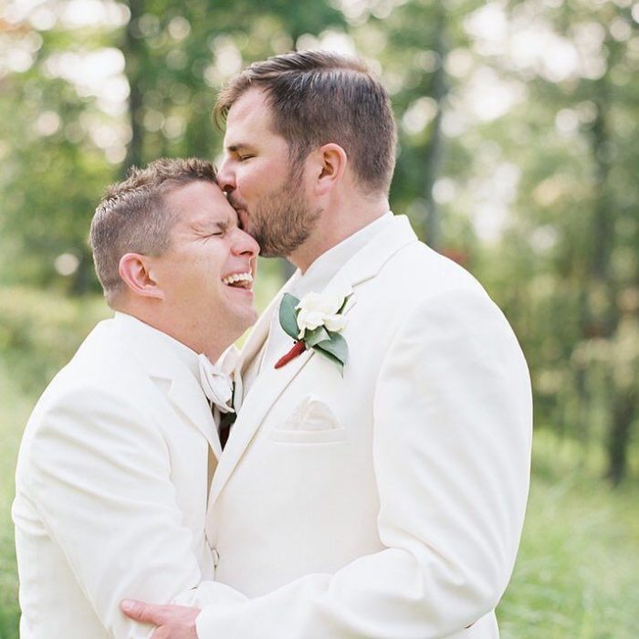 Pareja gay besándose la frente el día de su boda 