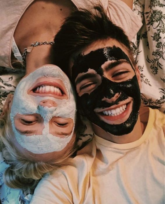 Pareja de novios sonriendo mientras se ponen mascarillas faciales