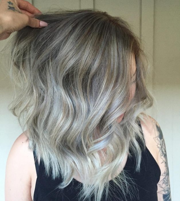 Chica usando un corte de cabello long bob en capas con un tinte en tonos gris 