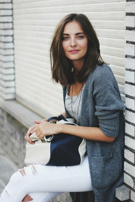 Chica con un corte de cabello long bob en capas, sentada en la banqueta 