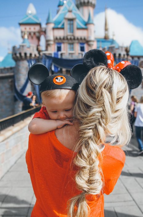 Chica cargando un bebé con orejas de mickey en Disney 