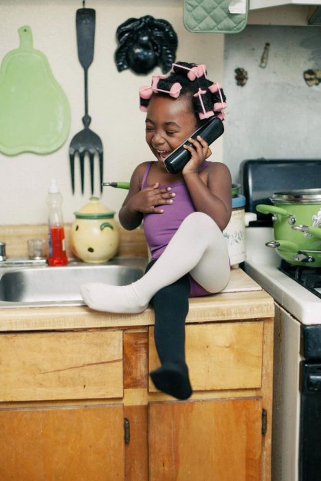 Niña de color hablando por teléfono felizmente 