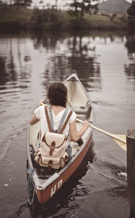 Chica remando un bote en un lago 