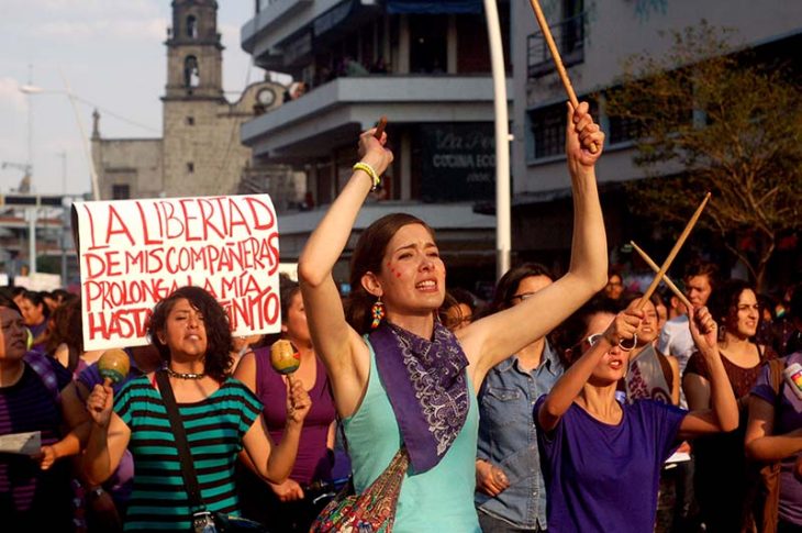 mujeres feministas en marcha en contra de violencia pancartas y palos 