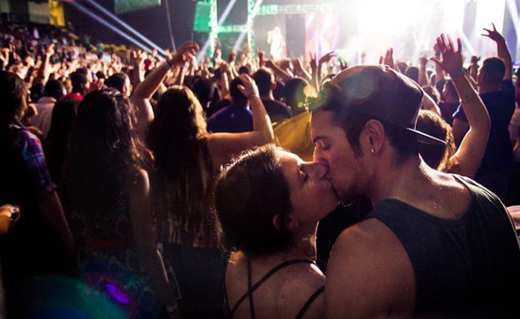 mujer besando en a novio en concierto 