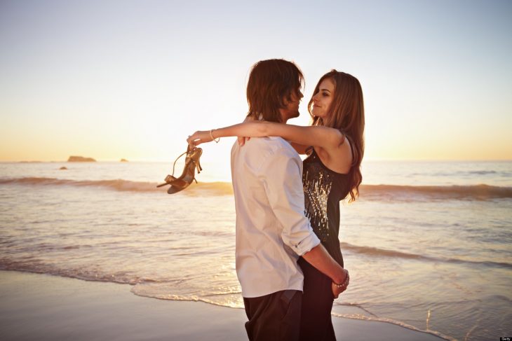 Pareja de jóvenes abrazándose en la playa.