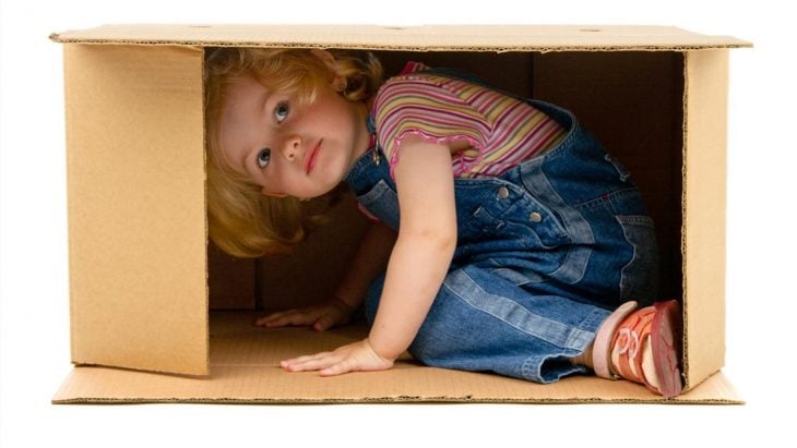 niña pequeña se esconde en caja