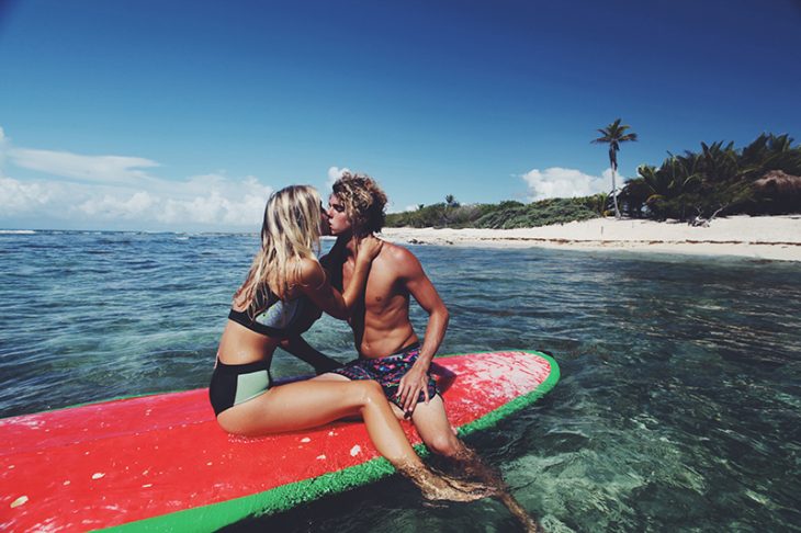 mujer rubia y hombre en tabla de surf en playa 