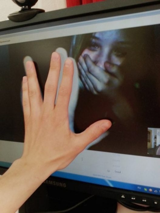 mujer llorando en videollamada y manos en la pantalla 