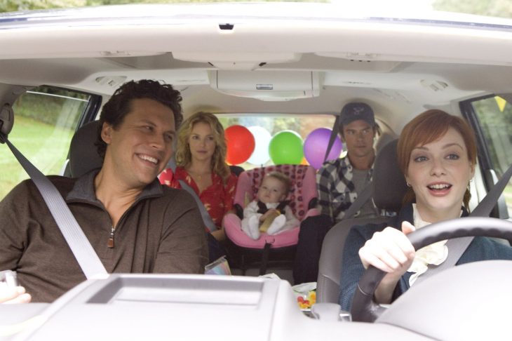 familia en el coche hombre de cabello negro y mujer pelirroja manejando 