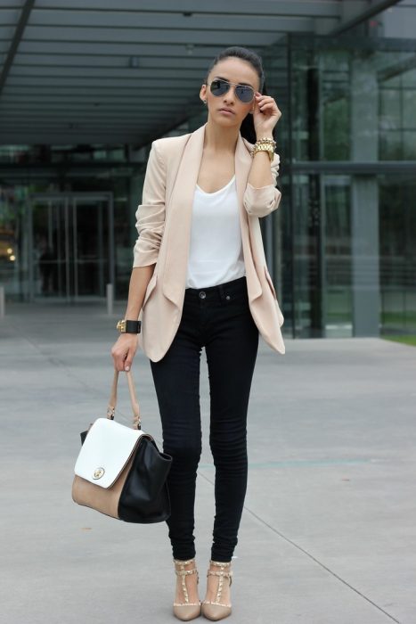 Chica usando unos jeans de color negro con un blazer en color café y blusa blanca 