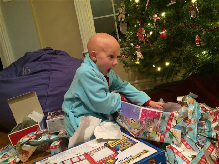Niña que sufre de alopecia areata abriendo sus regalos de navidad