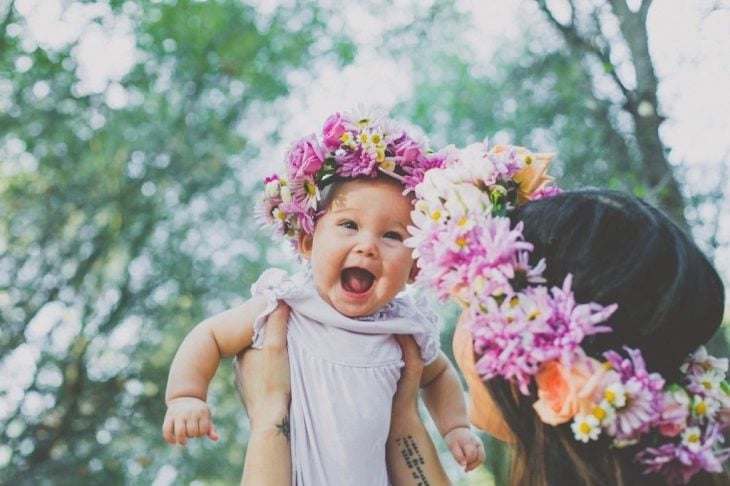 Chica cargando a una bebé con una corona de flores 