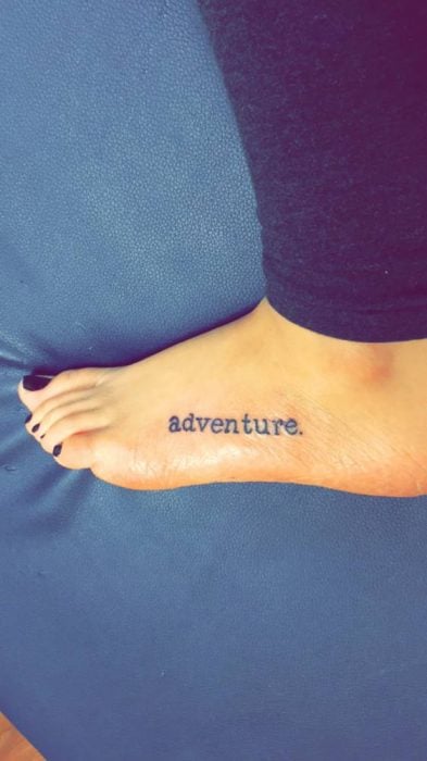  tatuaje en el pie con la palabra adventure 