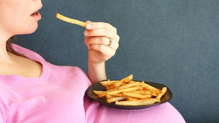 Chica embarazada comiendo papas fritas