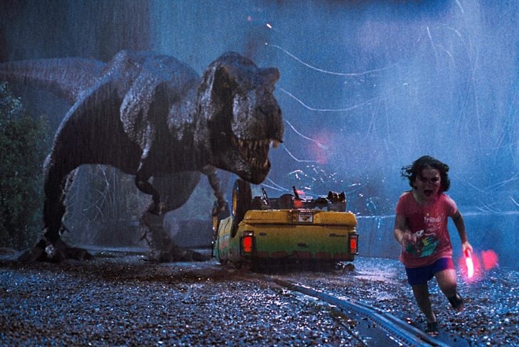 niña corriendo con dinosaurio atrás