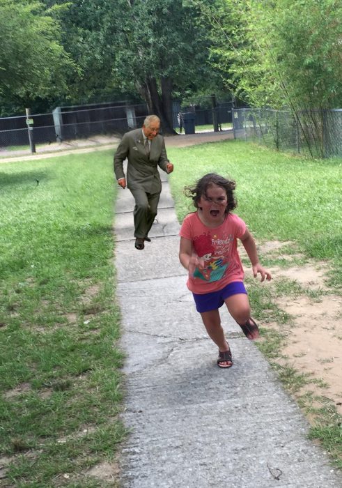 niña corriendo con imagen del príncipe carlos detrás