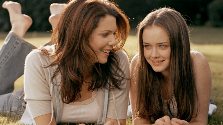 Escena de la serie gilmore gils chicas conversando mientras están recostadas en el pasto 