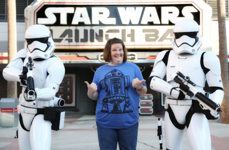 Mujer de camisa azul sonríe al lado de soldados Star Wars 