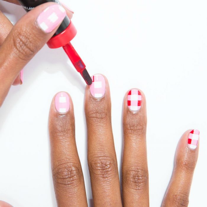 manos de mujer morena con diseño de cuadros rojos blancos y rosas 