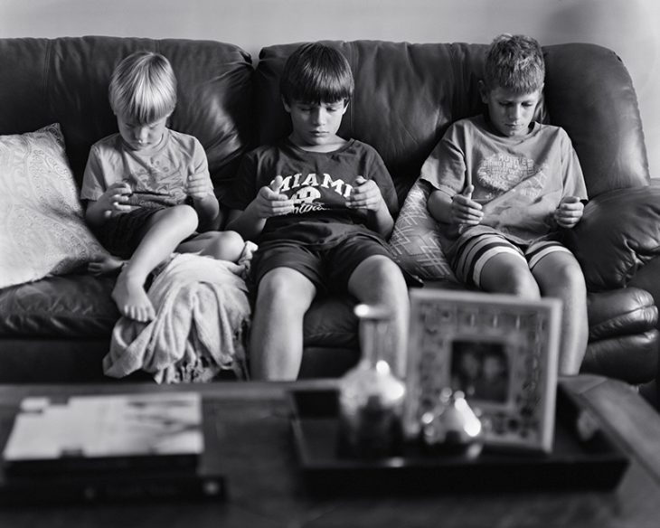 niños en un sillon sentados sin viendo sus manos 